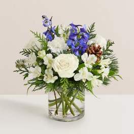 White roses and blue flowers in a clear glass vase