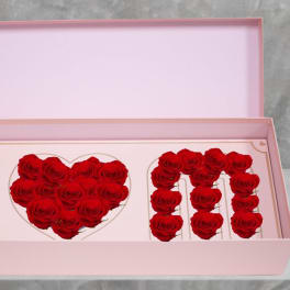 Pink gift box with red roses arranged in the letters M and N and a heart