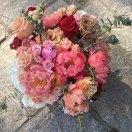 Round bouquet of pink, peach, and red flowers with eucalyptus