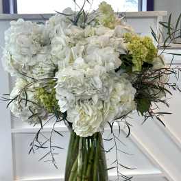 White hydrangea arrangement in a glass vase with pebbles