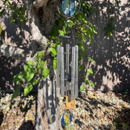 Stained-glass and metal wind chime hanging from a tree branch