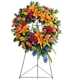 Large floral wreath on a standing easel with orange, pink, yellow, and blue flowers
