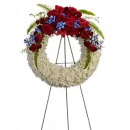Standing funeral wreath with red and white flowers and blue accents