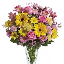 Bouquet of pink roses and yellow daisies in a clear glass vase