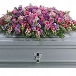 Pink and purple floral casket spray on a gray casket