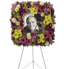 Standing floral wreath around a framed black-and-white portrait on an easel