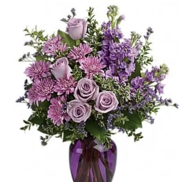 Lavender roses and purple flowers in a purple glass vase