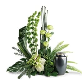 Green floral funeral arrangement with a dark urn