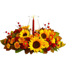 Autumn floral centerpiece with sunflowers and a candle in a glass hurricane