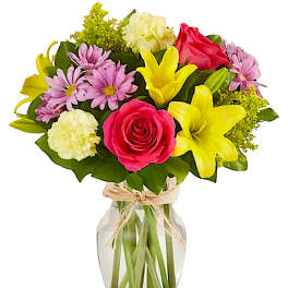 Mixed bouquet of pink roses, yellow lilies, and daisies in a glass vase