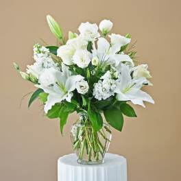 White lilies and lisianthus in a clear glass vase