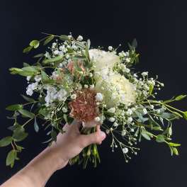 Handheld bouquet of white and blush flowers with airy greenery