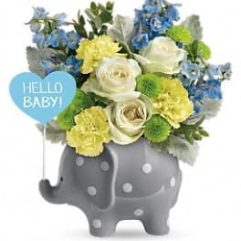 Blue and yellow flower arrangement in a gray elephant planter with a baby sign