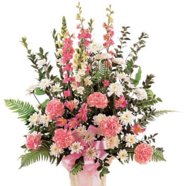 Pink and white floral arrangement in a decorative vase with a pink ribbon