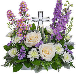 White roses and purple flowers arranged around a clear cross