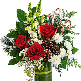 Red roses and white flowers in a green glass vase with candy canes