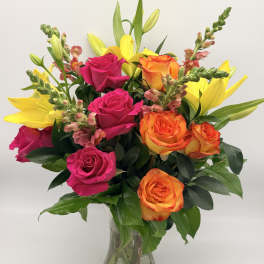 Bouquet of pink and orange roses with yellow lilies in a glass vase