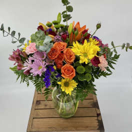Mixed bouquet of roses, lilies, and daisies in a glass vase