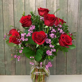 Red roses and pink filler flowers in a clear glass vase