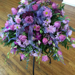 Pink and purple floral arrangement on a black stand with ribbon