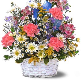 Mixed bouquet in a white woven basket with pink carnations and daisies