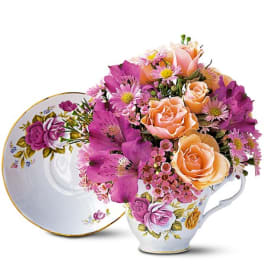 Bouquet of peach and purple flowers in a floral teacup
