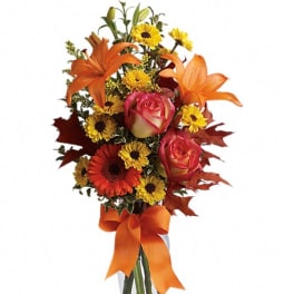 Orange lilies and roses with yellow daisies in a glass vase