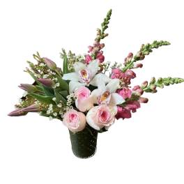 Pink roses, white orchids, and pink snapdragons arranged in a green textured glass vase