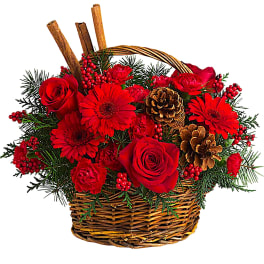 Red roses and gerbera daisies in a wicker basket with pinecones