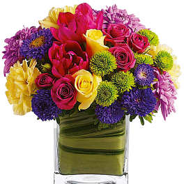 Colorful bouquet of roses, tulips, and mums in a clear glass vase
