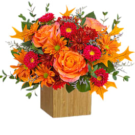 Orange and pink floral arrangement in a wooden cube vase