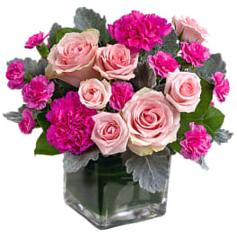 Pink roses and magenta carnations in a square glass vase