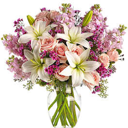 Pink roses and white lilies arranged in a clear glass vase
