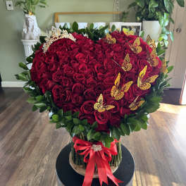 Heart-shaped bouquet of red roses with butterflies and a red ribbon