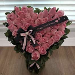 Heart-shaped bouquet of pink roses with a birthday ribbon