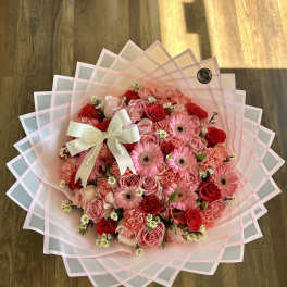 Pink and red rose bouquet with gerbera daisies and a white ribbon bow