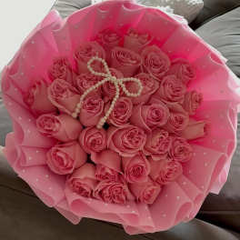 Bouquet of pink roses wrapped in pink paper with pearl accents