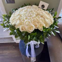 Large bouquet of white roses with a green leaf border and white ribbon