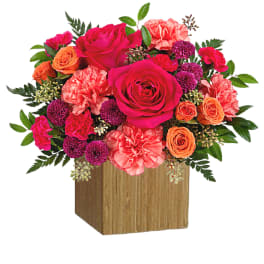 Bright mixed bouquet of roses and carnations in a wooden cube vase