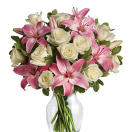 Arrangement of white roses and pink lilies in a clear glass vase
