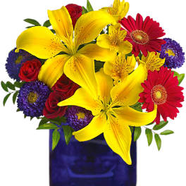 Bouquet of yellow lilies, red roses, and purple daisies in a blue vase