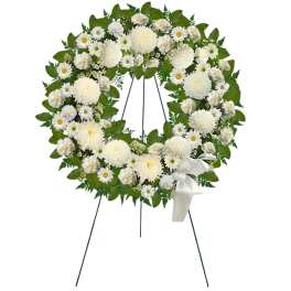 White floral funeral wreath on a stand with a ribbon bow