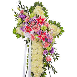 Standing floral spray with pink lilies, roses, and white blooms on a cross-shaped base