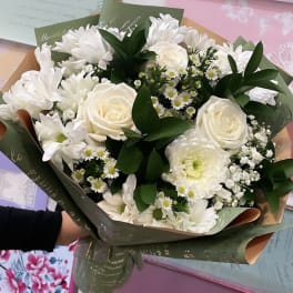 White bouquet of roses, chrysanthemums, and small daisies wrapped in green printed paper
