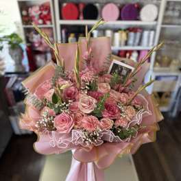 Pink rose bouquet with carnations and tall buds in pastel wrapping