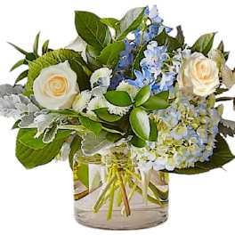 White roses and blue hydrangeas in a clear glass vase