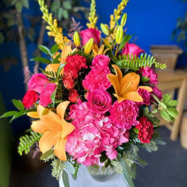Bright pink and orange floral arrangement in a white vase