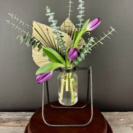 Purple tulips in a glass jar with dried palm and eucalyptus