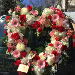 Heart-shaped floral wreath with red, pink, and white flowers on a vehicle