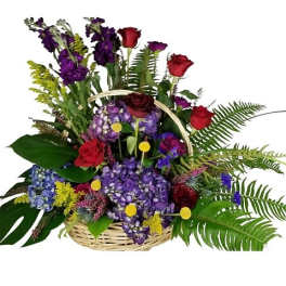 Basket arrangement with purple hydrangeas, red roses, tall purple flowers and lush ferns.